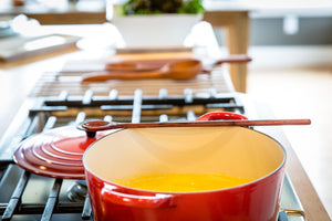 wood tasting spoon sitting on le creuset dutch oven with soup - Earlywood