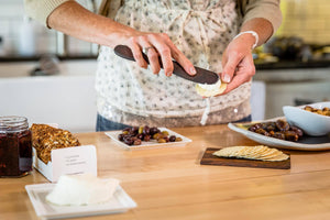 handmade wooden cheese knife spreading cheese on crackers - Earlywood